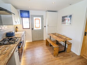 Una cocina con encimera de madera, estufa a gas, horno empotrado, un lavamanos y una ventana con puerta de vidrio decorativa.