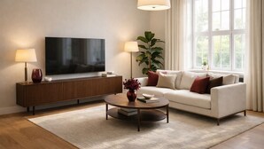 A modern living room with a flat-screen TV, a sofa, a coffee table, and a large window with curtains. - Elegant 2-Bed 2-Bath in Covent Garden (London)