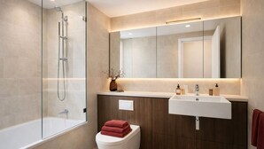 A modern bathroom with a glass-enclosed shower, a white toilet, a wooden vanity with a sink, and a mirror. - Elegant 2-Bed 2-Bath in Covent Garden (London)