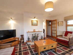 Ein Wohnzimmer mit Fernseher, Kamin, Sofa und einem gemusterten Teppich.