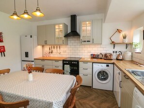 Una cocina compacta con una mesa de comedor, electrodomésticos integrados y una lámpara colgante.