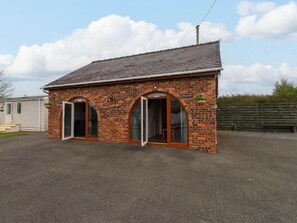 A brick building with two arched doorways, a sign above the right door, and a small garden area. - Bryn Mair, Llangefni (Llangefni)
