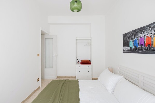Une chambre à coucher avec un lit, une commode, un miroir et un tableau accroché au mur.