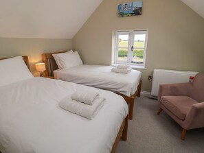 A bedroom with two beds, a chair, a window with a view, and a radiator. - 6 Gravel Hill, Burnham Market (King's Lynn)