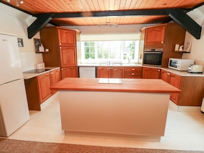 A kitchen with wooden cabinets, a central island, a refrigerator, a microwave, and a toaster.