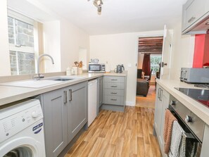 Eine kleine Küche mit Waschmaschine, Mikrowelle und Backofen.