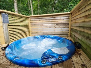 Un jacuzzi en una terraza de madera rodeado de árboles.