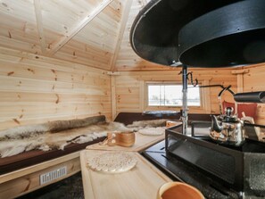 A wooden cabin interior with a fur-lined window seat, a stove, and wooden furniture. - 1 Gilpin House, Levens Cumbria (Kendal)