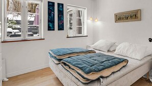 Ein Schlafzimmer mit einem Bett, zwei Fenstern und Wandbildern.