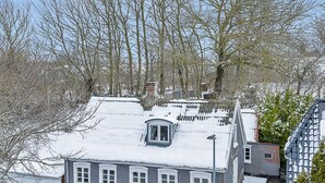 Ein Wohngebäude mit geneigtem Dach, zahlreichen Fenstern und einem sichtbaren Schornstein.