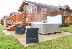 A wooden cabin with a hot tub, outdoor seating, and a staircase leading to the deck. - Fairway View Lodge, Felton (Morpeth)