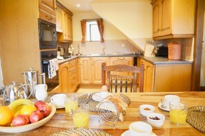 Une cuisine avec des meubles en bois, un four à micro-ondes, un évier et un coin petit-déjeuner avec des fruits, des œufs et du jus.