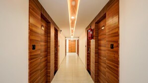 A hallway with wooden paneling, a tiled floor, and a fire extinguisher mounted on the wall. - Deluxe Onyx Hotel (Bengaluru)