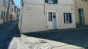 A two-story building with a white facade and green shutters, a door, and a small window. - Charming 1-bedroom house in Azille perfect for a relaxing getaway (Azille)