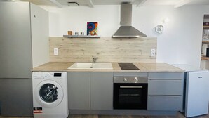 A compact kitchen with a washing machine, oven, and sink. - Charming 1-bedroom house in Azille perfect for a relaxing getaway (Azille)