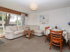A living room with a sofa, dining table, chairs, and a bookshelf.