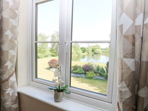 Een raam met uitzicht op een meer, een potorkidee en kamer met behang.
