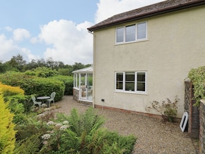 A house with a patio, a conservatory, and a garden with various plants.