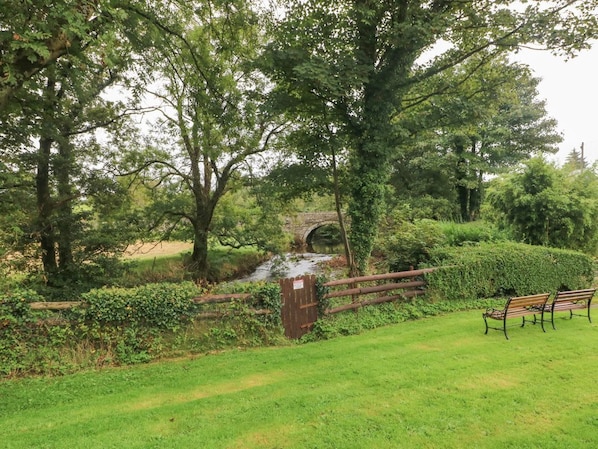 Un parc avec un pont en bois, un banc et une porte.