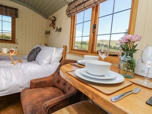 A cozy room with a bed, a wooden table with a bowl and wine glass, and a chair. - Poppy: A Charming Getaway in Rhayader (Rhayader)