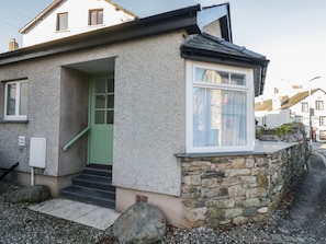 A small house with a stone wall, a green door, and a window.