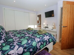 Ein Schlafzimmer mit einem Bett, einem Fernseher, einer Holztür und einem weißen Kleiderschrank.