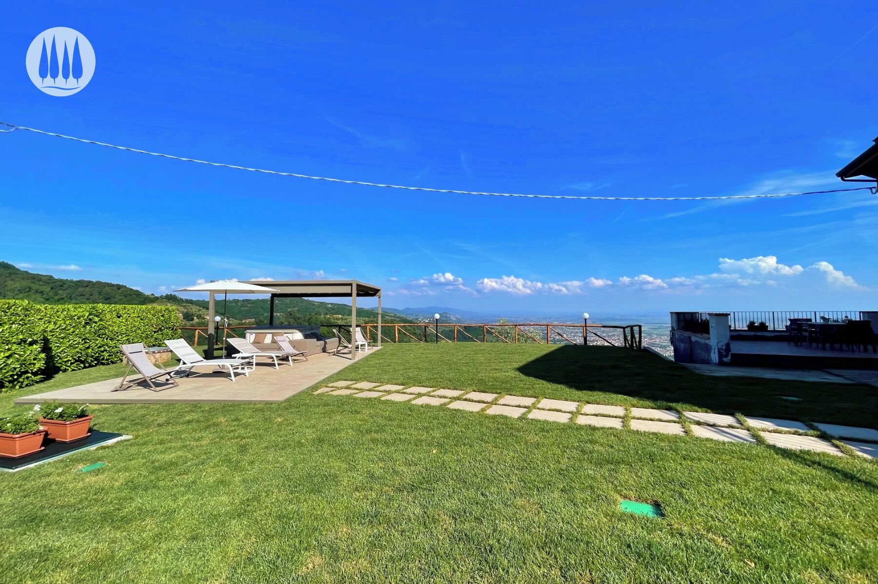 En baghave med et pergola, liggestole, grillområde og udsigt over byen.