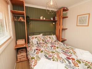 Un dormitorio con una cama, estanterías de madera, una planta colgante y un cuadro en la pared.