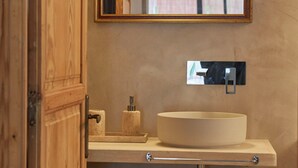 A bathroom with a wooden vanity, a round sink, a mirror, and a towel dispenser. - Studio Suite with private patio in Aiguablava-Begur (CT)
