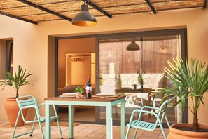 A patio with a table, chairs, potted plants, and a bottle of wine. - Studio Suite with private patio in Aiguablava-Begur (CT)