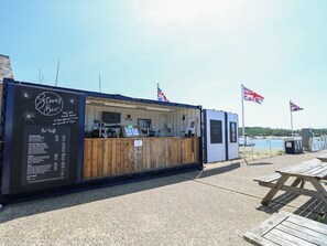 A food truck named 'Steve's Bar' with a menu board, a wooden counter, and flags.