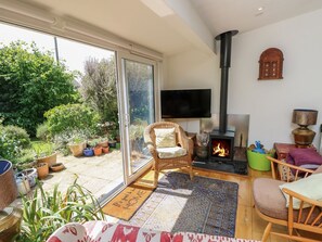 A living room with a fireplace, a television, and a large window overlooking a garden.