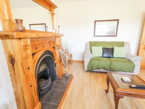 Una sala de estar con chimenea, un sofá con una manta verde y una mesa de centro de madera.