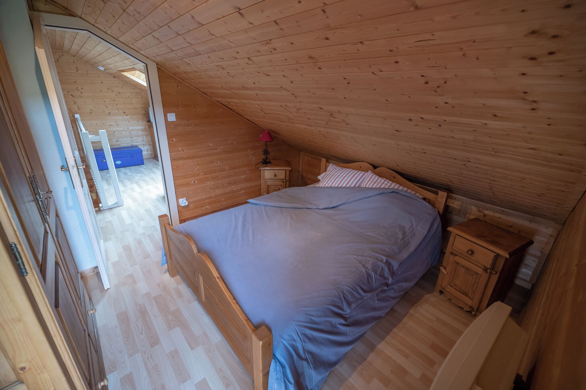 Une chambre dans une cabane en bois, avec un lit, une table de chevet et une petite commode.