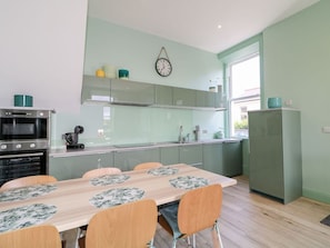 A modern kitchen with a dining table, chairs, and a clock on the wall.