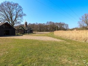 A rural landscape with a barn, a small building with a green roof, and a tower-like structure.