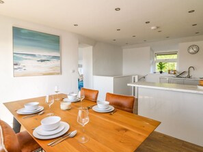 A dining area with a wooden table set for four, white plates, and wine glasses. - 1 Gibraltar Terrace, Aberfyfi. (Aberdovey)