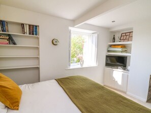A bedroom with a bed, a window, a bookshelf, and a TV. - 1 Gibraltar Terrace, Aberfyfi. (Aberdovey)