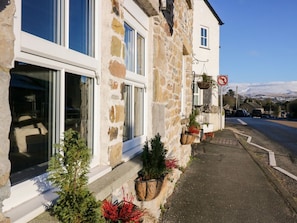 A stone building with large windows, a no parking sign, and potted plants along the sidewalk. - Holme Fell View is in Sedbergh (Sedbergh)