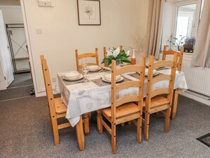Ein Esstisch mit Geschirr, Gläsern und Besteck, umgeben von Holzstühlen.