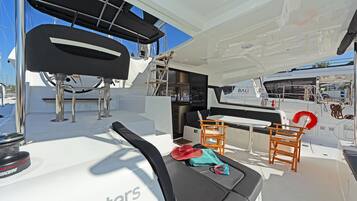 A boat's interior with a seating area, a table, and a lifebuoy.