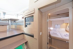 Un intérieur compact et bien éclairé, comprenant un lit, un panneau de commande et un espace salon.