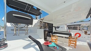 A yacht's deck with seating, a table, and a lifebuoy.