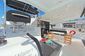 A yacht's deck with seating, a table, and a lifebuoy.