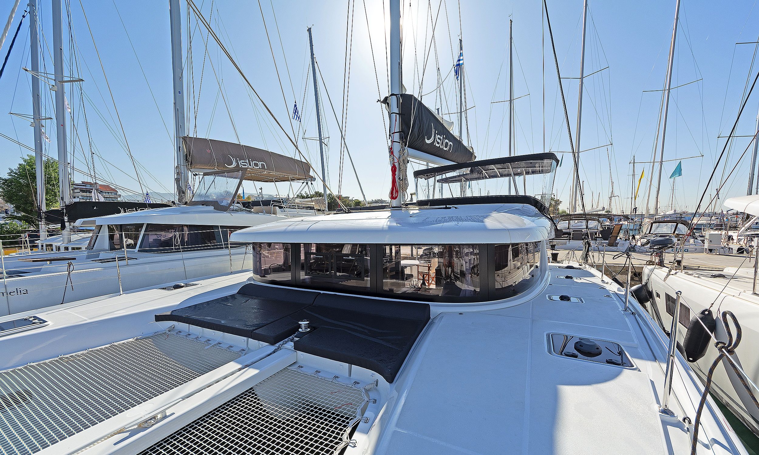 A marina with multiple sailboats docked, featuring a covered deck area with seating and a view of the marina.