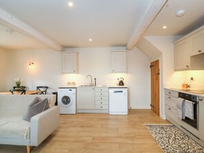 A compact kitchen with a washing machine, a dining area with a sofa, and a small table.