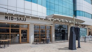 A restaurant with outdoor seating, a covered patio, and a modern building in the background. - Darent Royal Two Bedroom Kafd View Al Ghadir (Riyadh)
