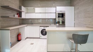A modern kitchen with white cabinets, a built-in oven, and a washing machine. - Darent Royal Two Bedroom Kafd View Al Ghadir (Riyadh)