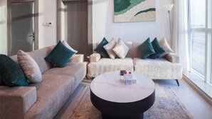 A living room with two sofas, a coffee table, and a painting on the wall. - Darent Royal Two Bedroom Kafd View Al Ghadir (Riyadh)