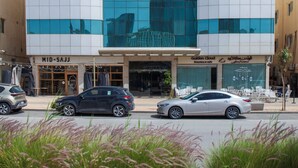 A modern building with a glass facade reflecting nearby structures. - Darent Royal Two Bedroom Kafd View Al Ghadir (Riyadh)